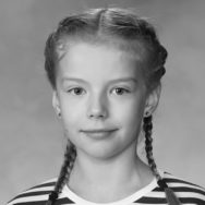 Nuori lettipäinen tyttö hymyilee kameralle