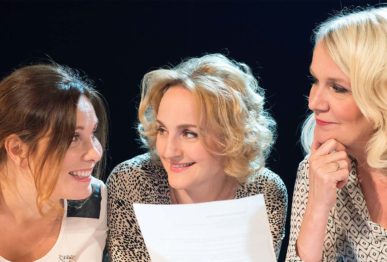Kolme naista hymyilee toisilleen kirjeen äärellä