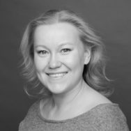 Nainen hymyilee kameralle mustavalkopotretissa