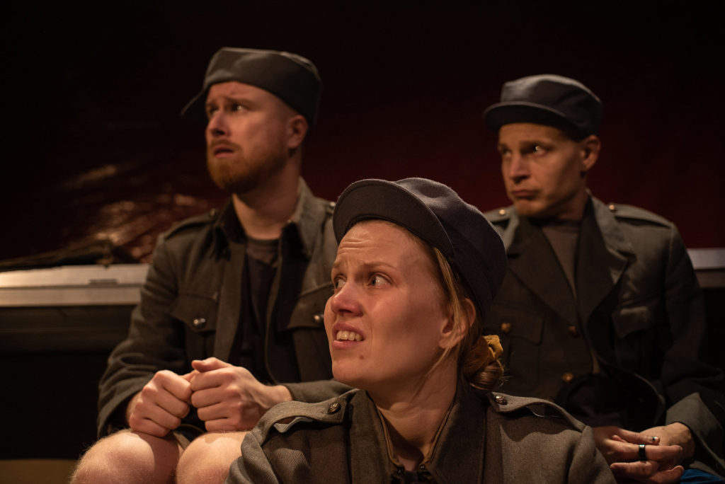 Kolme armeija-asuista näyttelijää kuuntelee