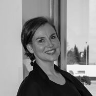 Nainen hymyilee kameralle mustavalkopotretissa