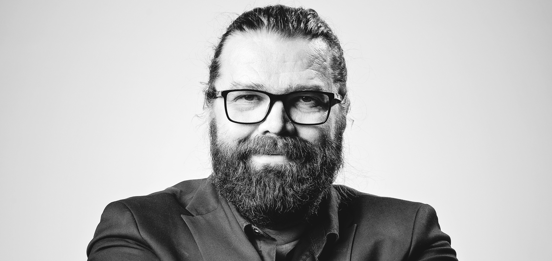 Partasuinen mies hymyilee mustavalkopotretissa
